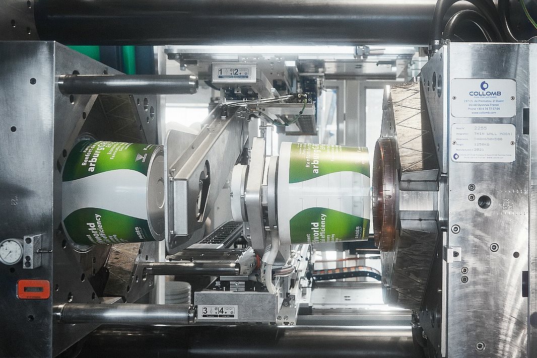 Arburg injection moulding machine producing in-mould labelled containers