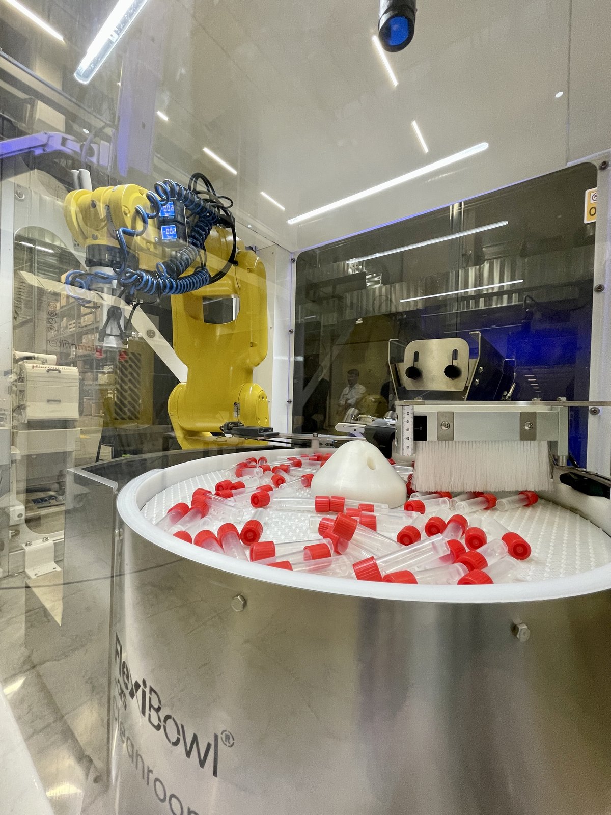 FlexiBowl feeding blood collection tubes with red caps in a cleanroom cell with a FANUC robot
