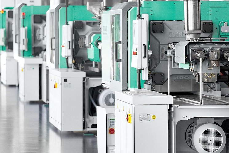 A line of Arburg Allrounder injection moulding machines on a production floor